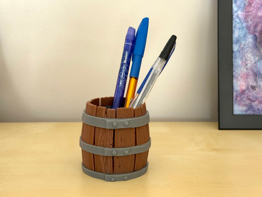 Wooden barrel-shaped pen holder with pens on a desk